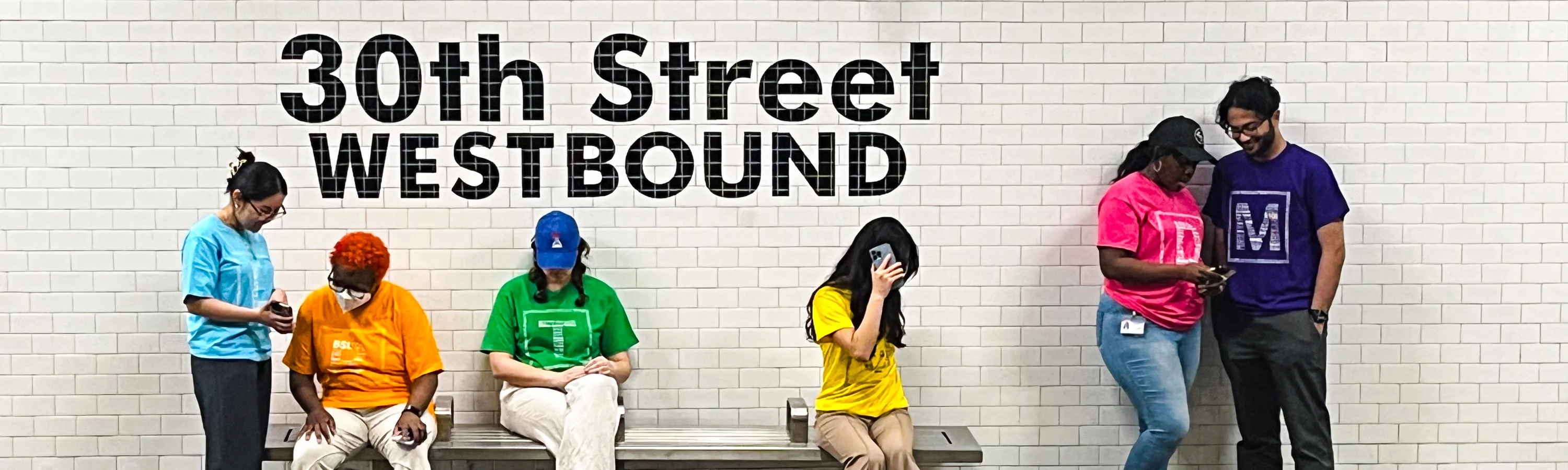 six people wearing SEPTA metro cloud t-shirts of different colors on a trolley platform